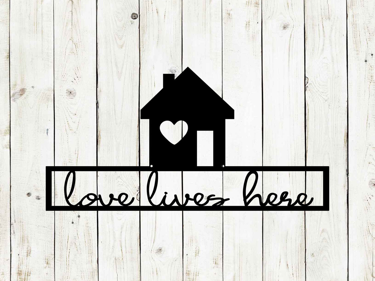 'Love Lives Here' metal sign with a house silhouette and heart, black on a white wood background.