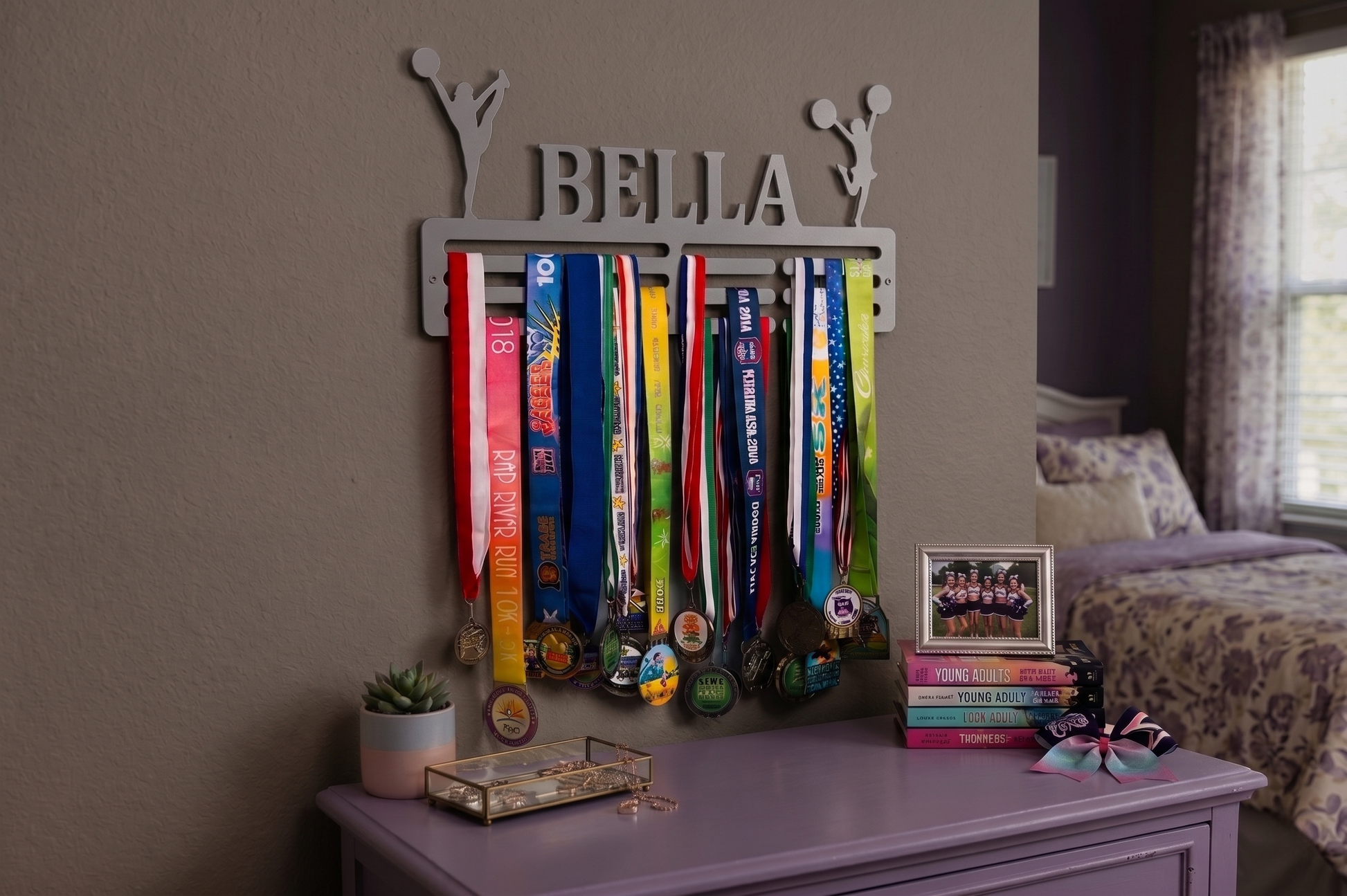 Medal display with 'BELLA' on a dresser in a bedroom setting. Cheerleader Medal and Award Hanger.  Cheer Award Display