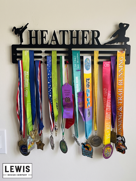 Medal holder with medals and ribbons on a wall, branded 'LEWIS Design Company'. Female Karate Medal and Award Display