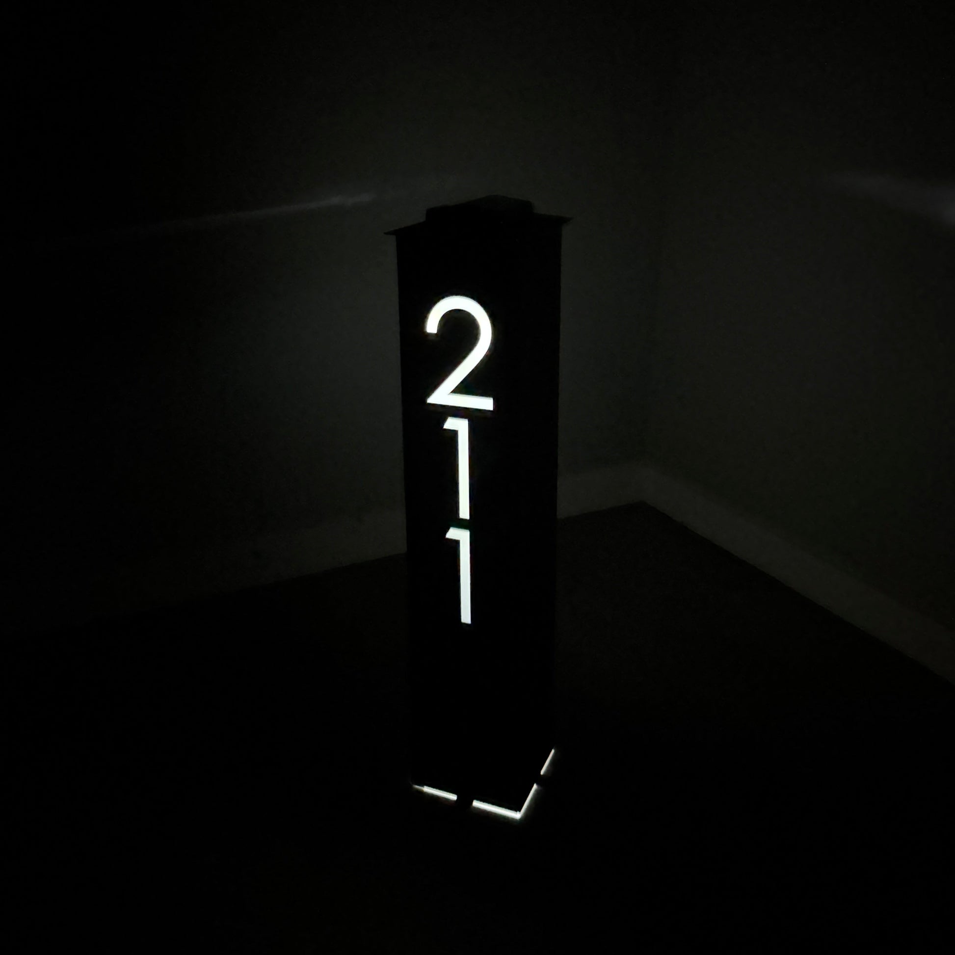 Lighted sign with the number '211' in a dark setting