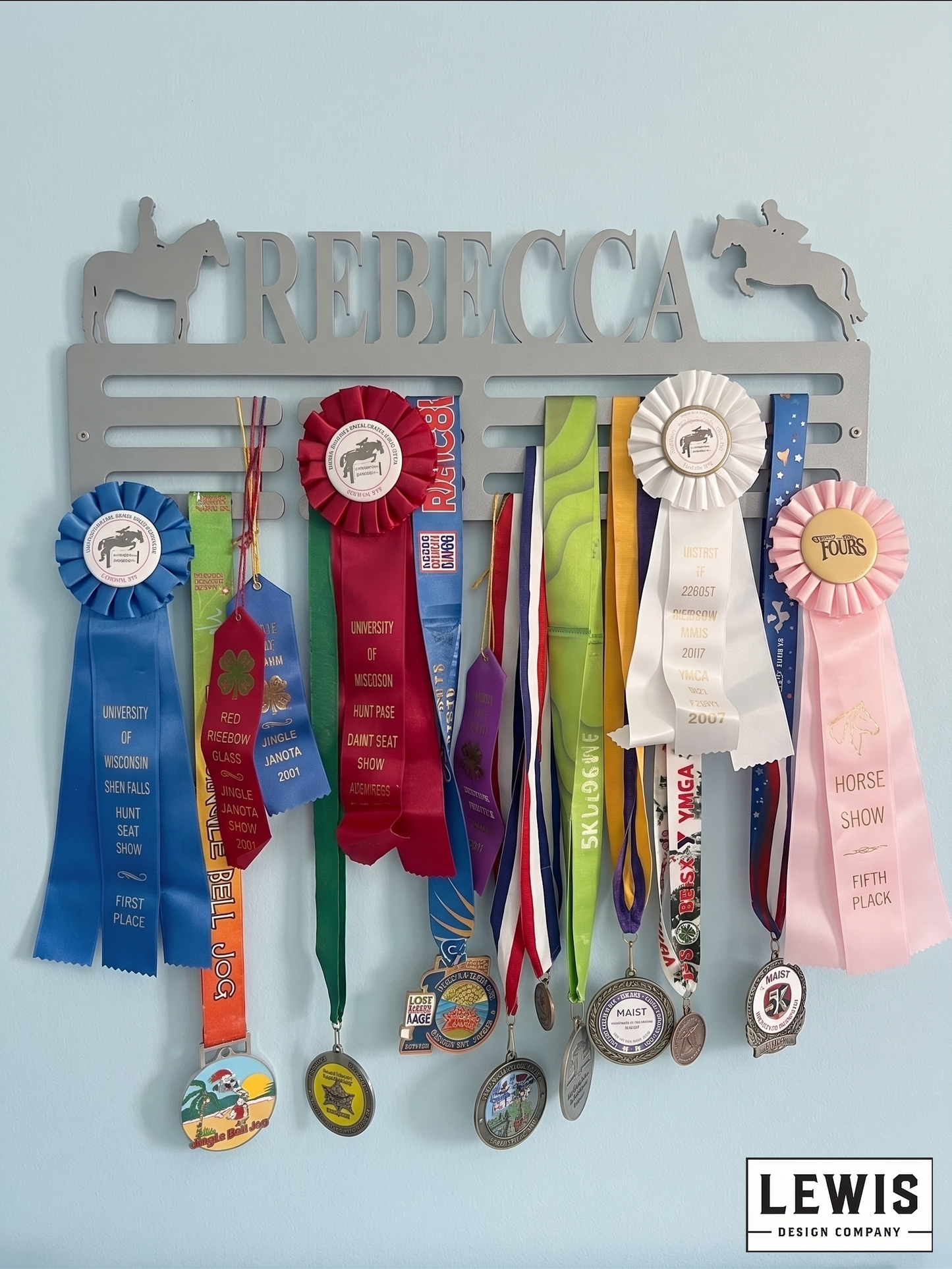 Medal and ribbon holder with personalized name 'Rebecca' against a light blue background, featuring various awards.