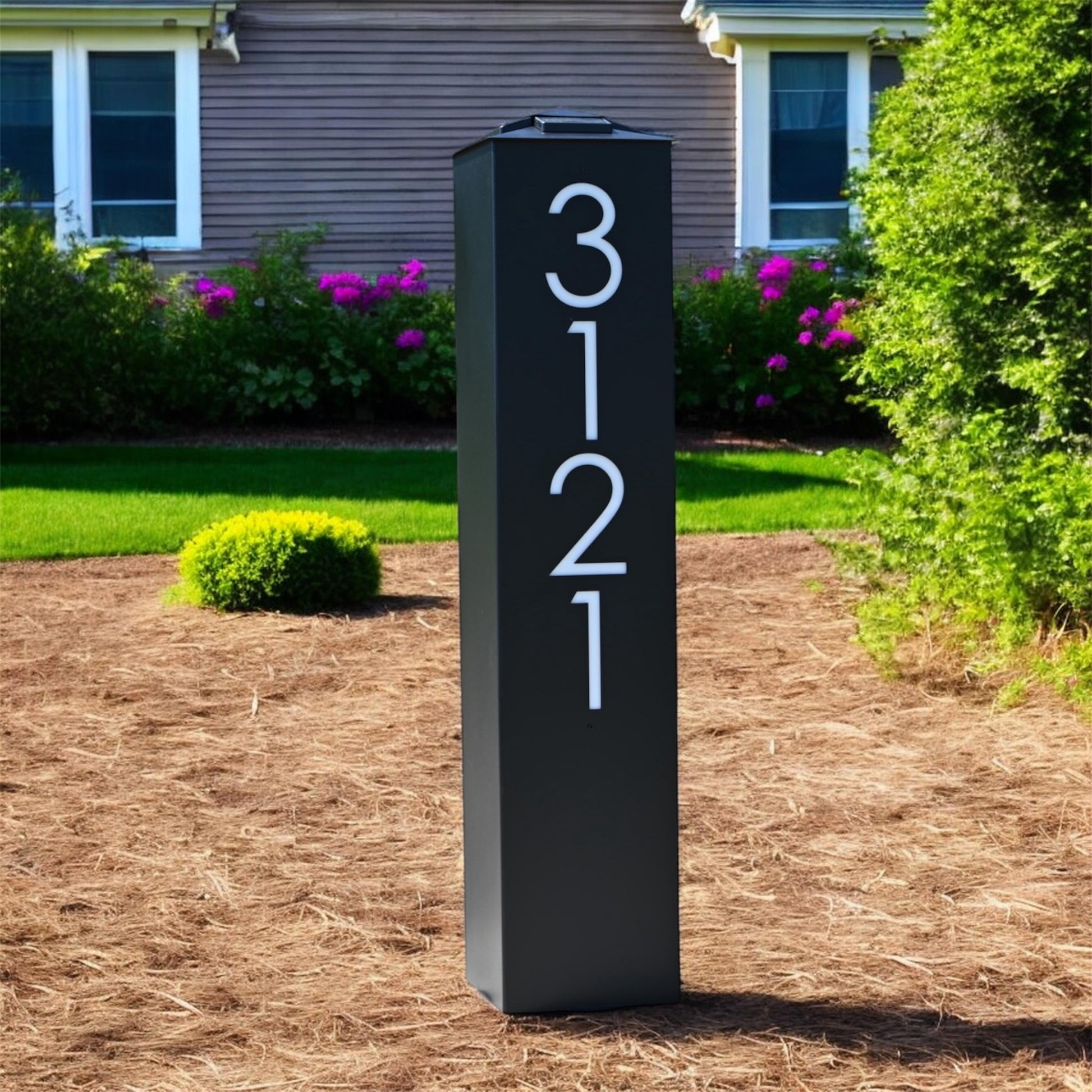 Modern black house number sign with '3121' on a garden background