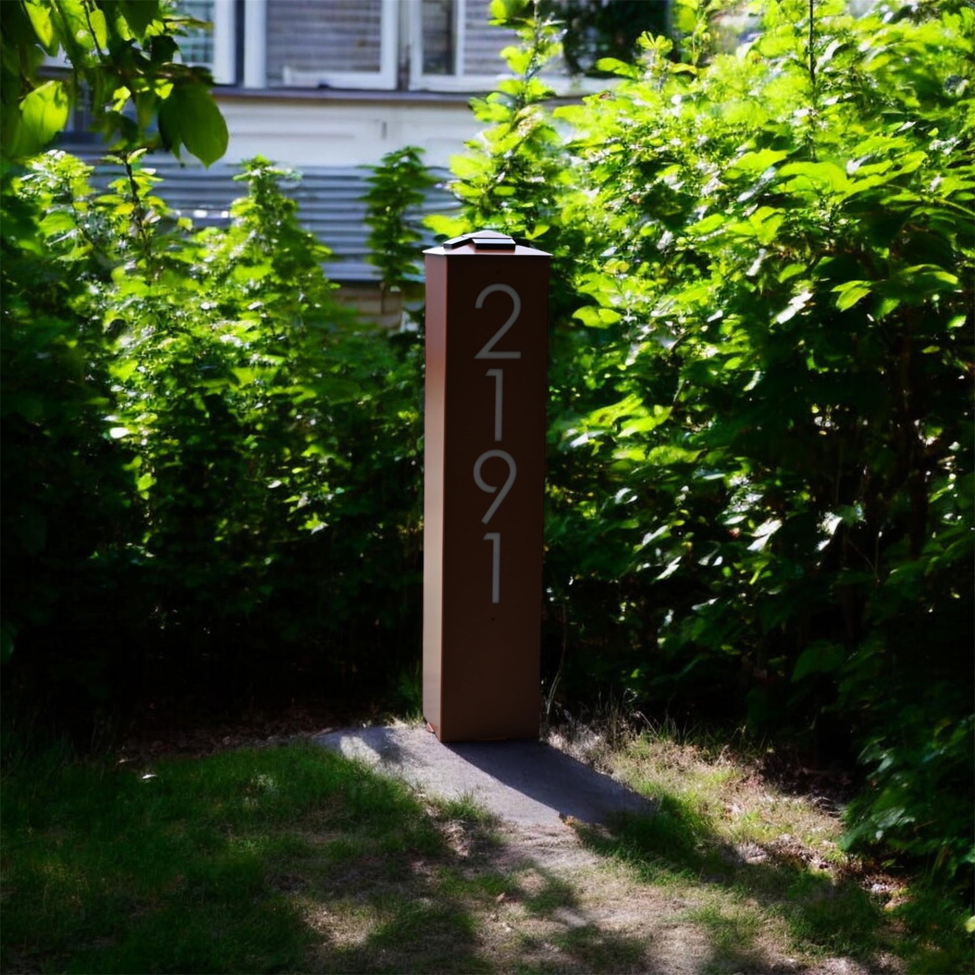 Modern house number signpost in a garden setting