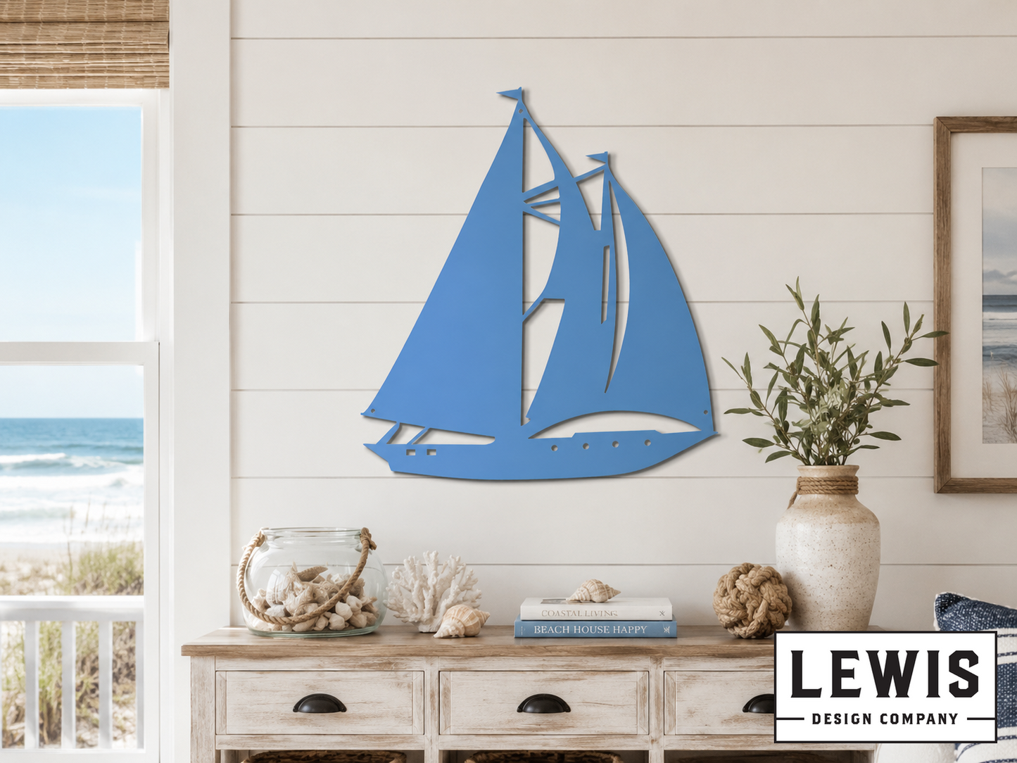 Blue sailboat wall art on a white wall with a coastal view.