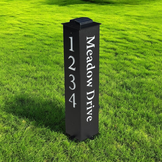 Black metal address signpost with 'Meadow Drive' on a grassy lawn